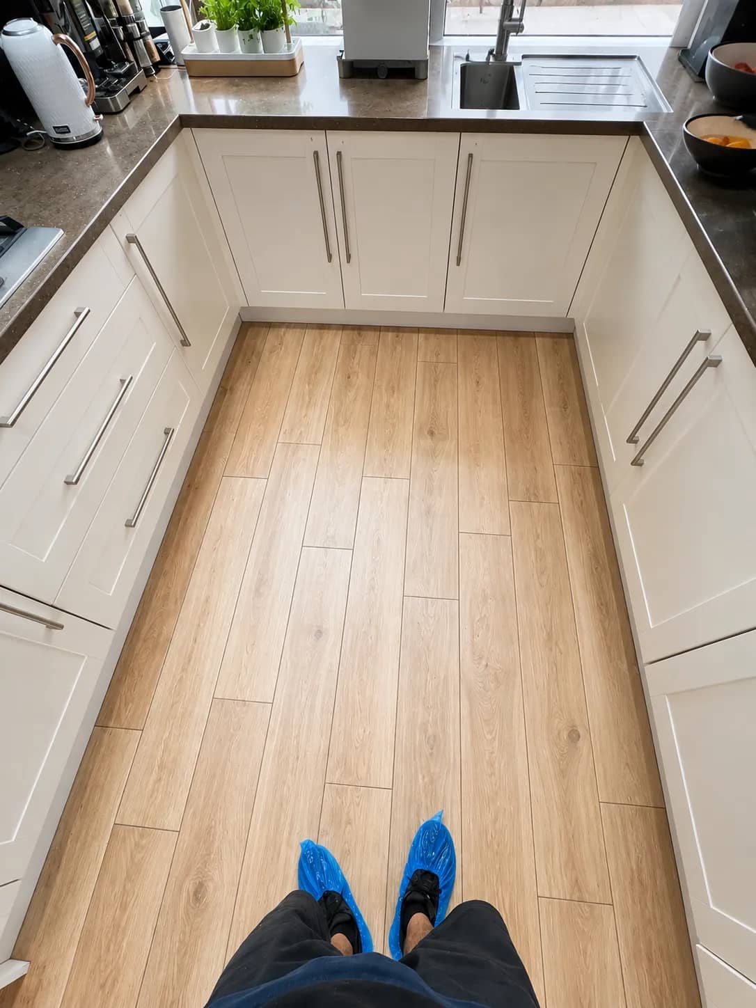 A shaker-style kitchen with a wood-effect floor left clean between the units.