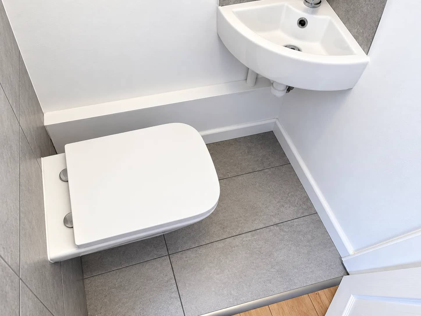 A compact bathroom with the toilet, basin and tiled floor left clean.