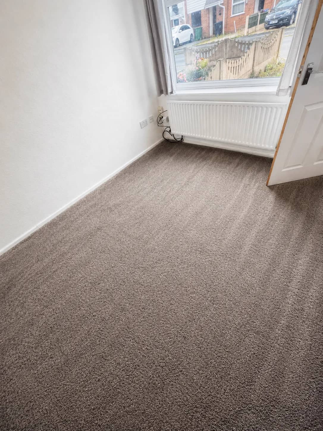 A freshly cleaned carpet groomed into even lines in an empty room.