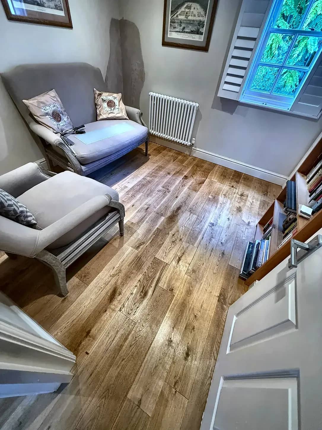 An oak floor cleaned through a lounge and around the furniture.