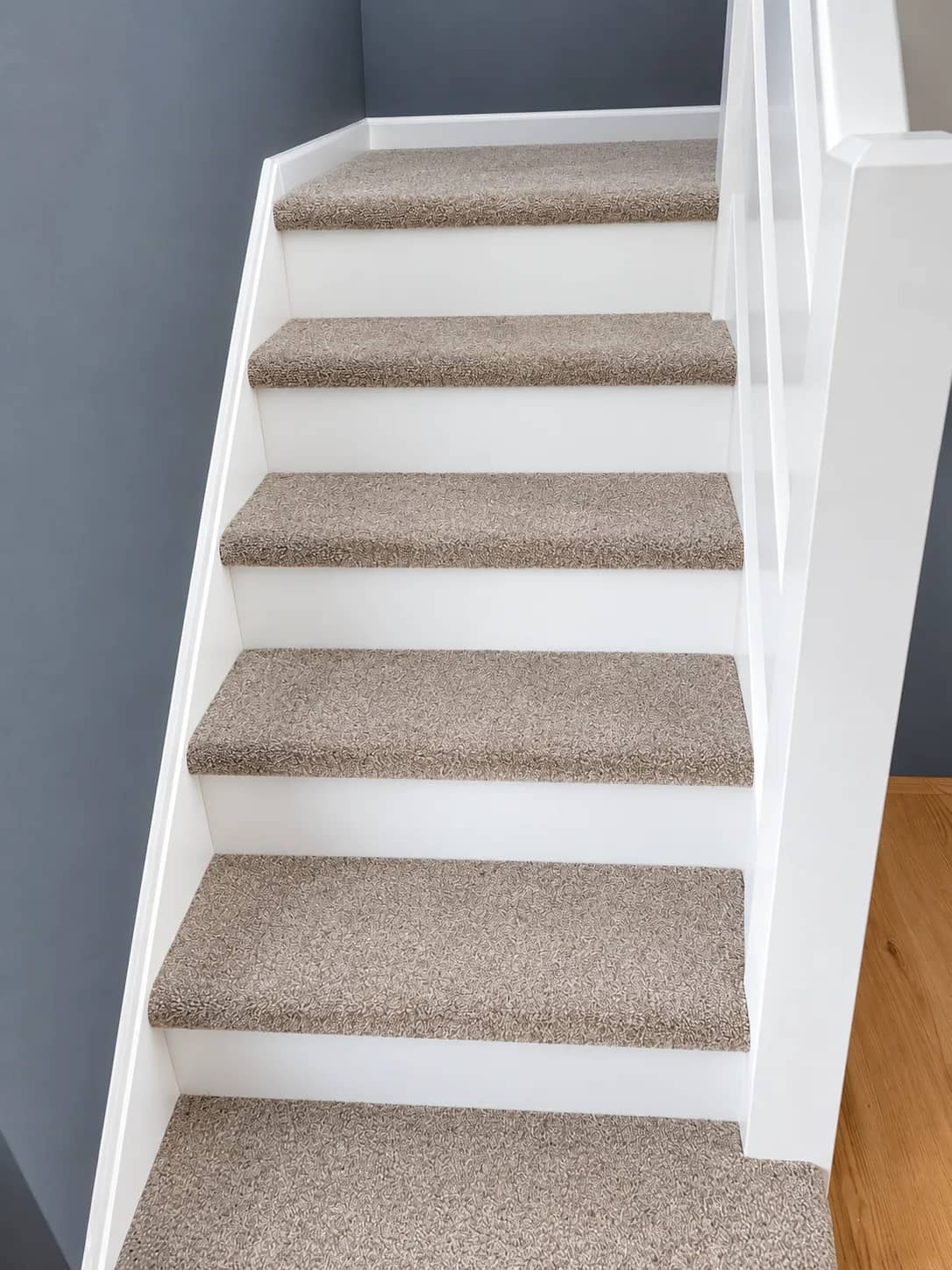 A stair carpet left clean against grey walls.