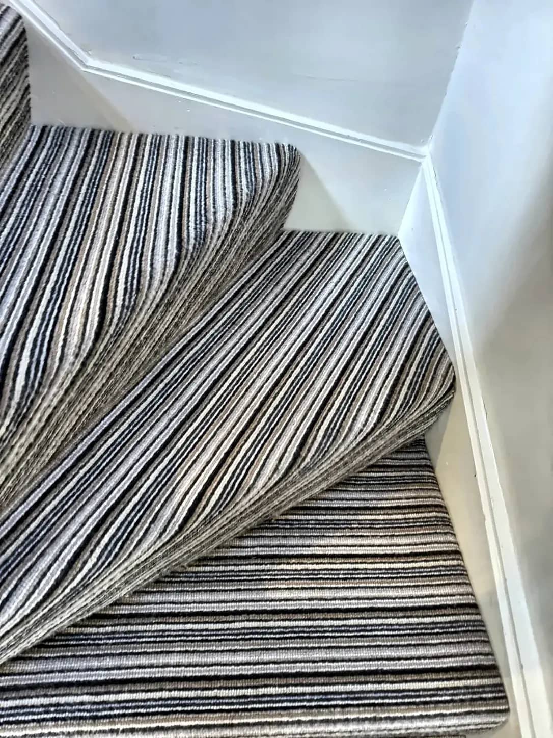 A striped stair carpet left clean up to the landing.