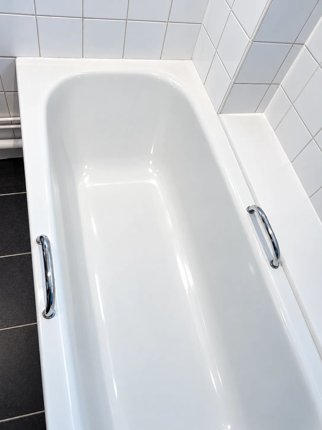 A white bath and tiled bathroom floor left clean after a deep clean.