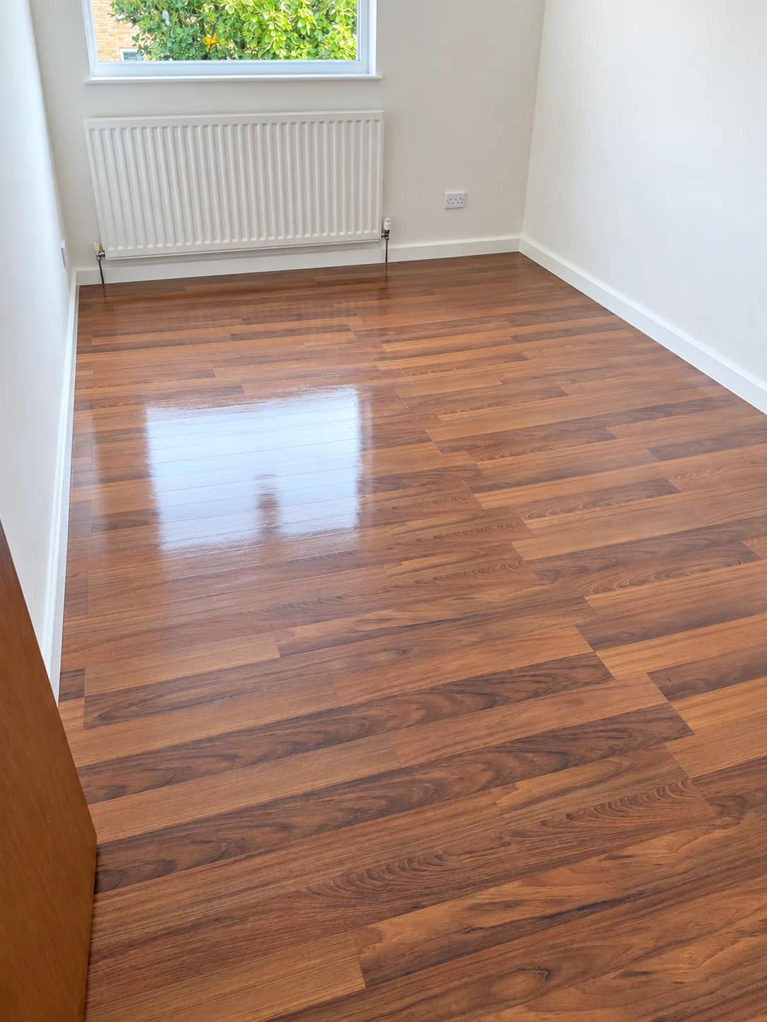 A dark wood laminate floor left clean beside a radiator